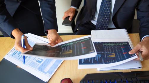 Investor and trader discussing statistic data, holding papers with financial charts and pen. Cropped shot. Broker job or trading concept